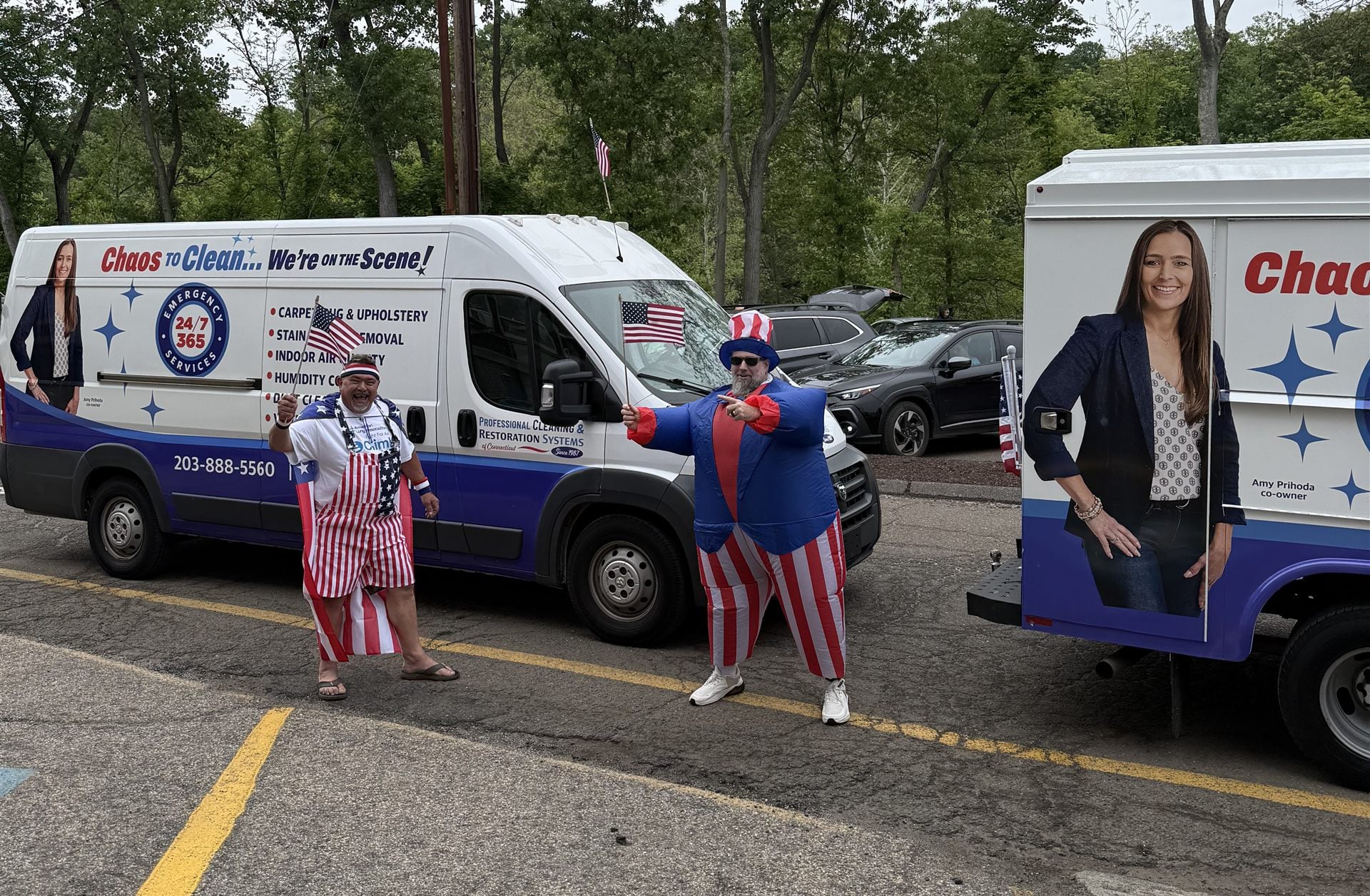 Adam and Curtis in Uncle Sam outfits with American flags in front of two wrapped Professional Cleaning & Restoration Systems of Connecticut trucks at the Memorial Day parade